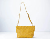 Yellow quilted handbag with a strap on a white background