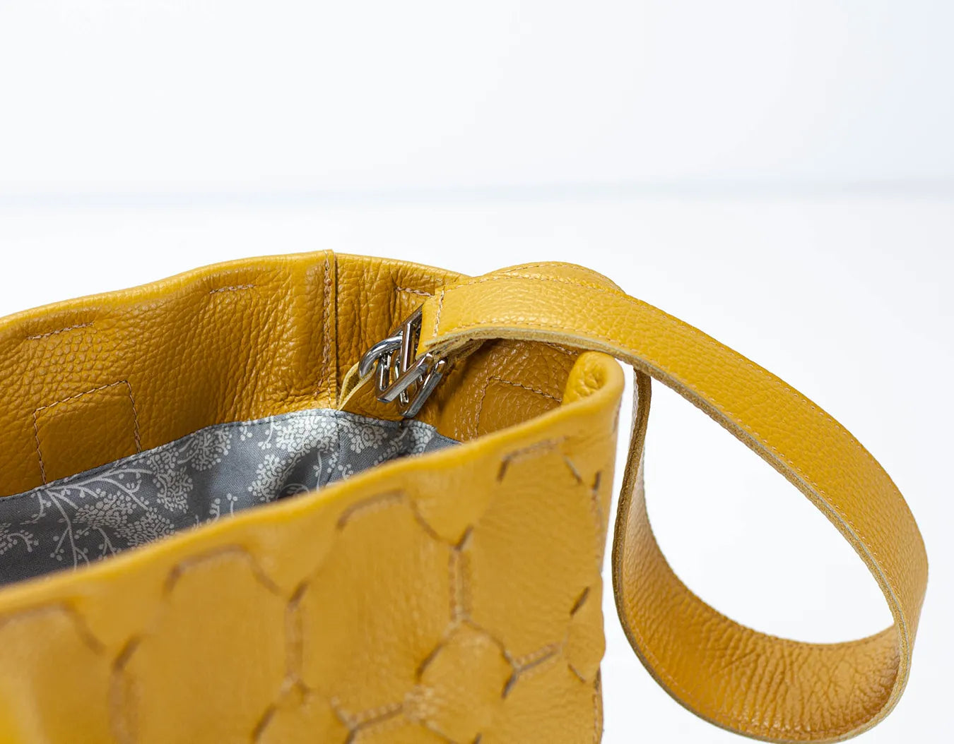 Yellow handbag with textured surface and strap on a white background