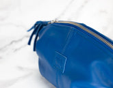 Blue leather pouch with a gold zipper on a white background