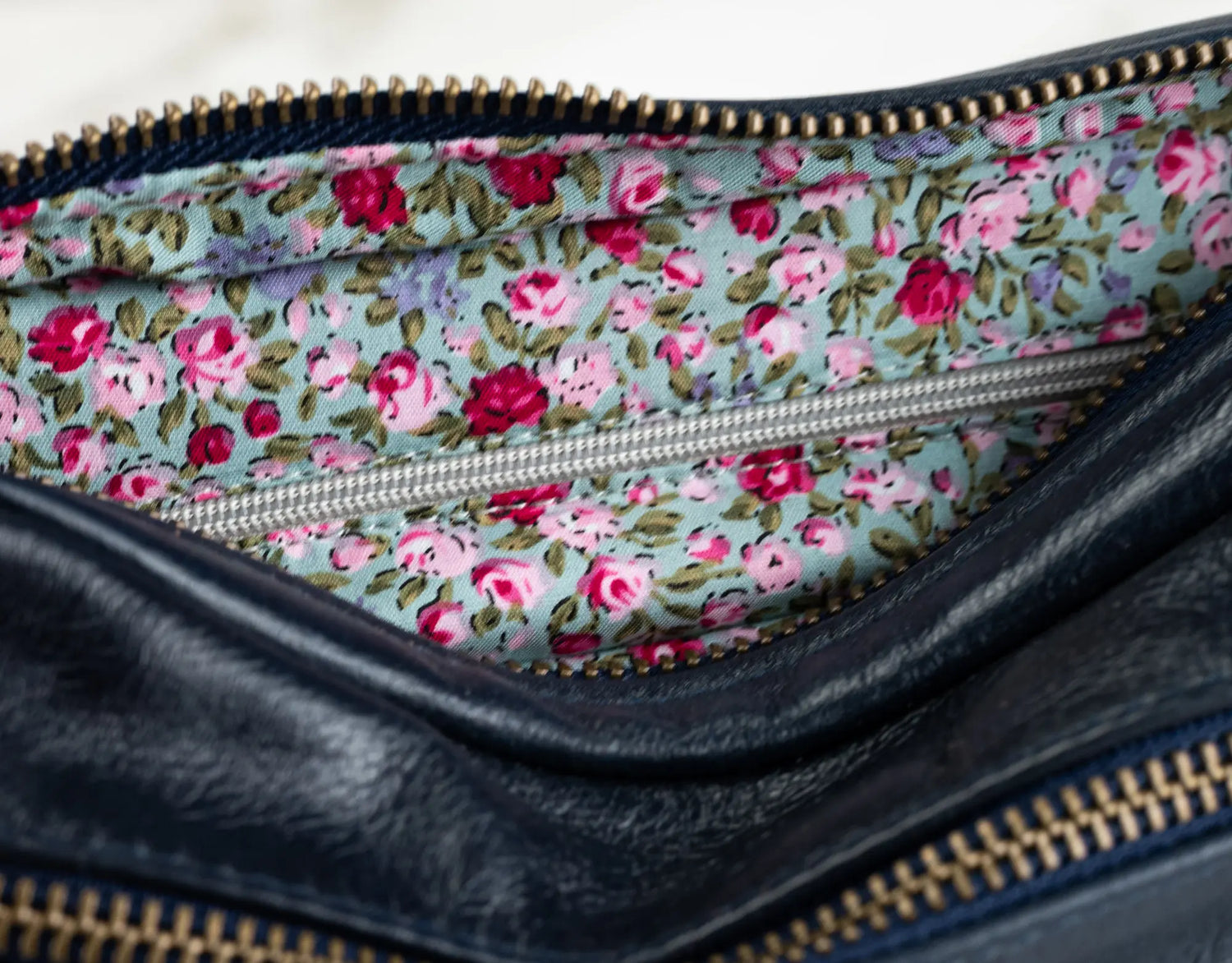 Floral-patterned interior of a black leather clutch bag.