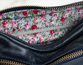 Floral-patterned interior of a black leather clutch bag.