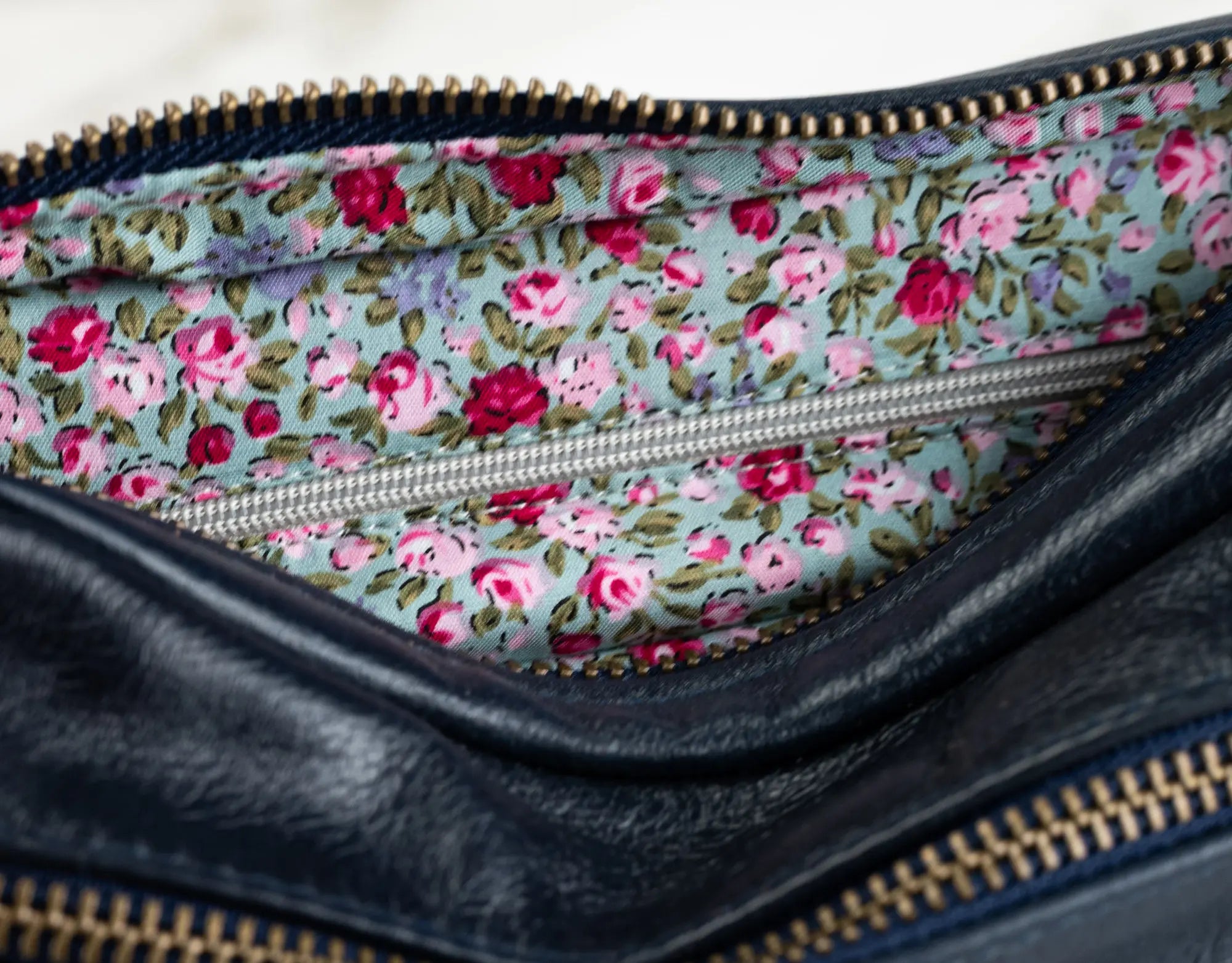 Floral-patterned interior of a black leather clutch bag.