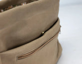 Close-up of a beige leather bag with a zipper on a white background