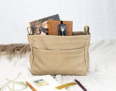 Beige fabric basket with books and stationery items on a white surface