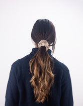 Person with long hair tied back with a scrunchie on a white background