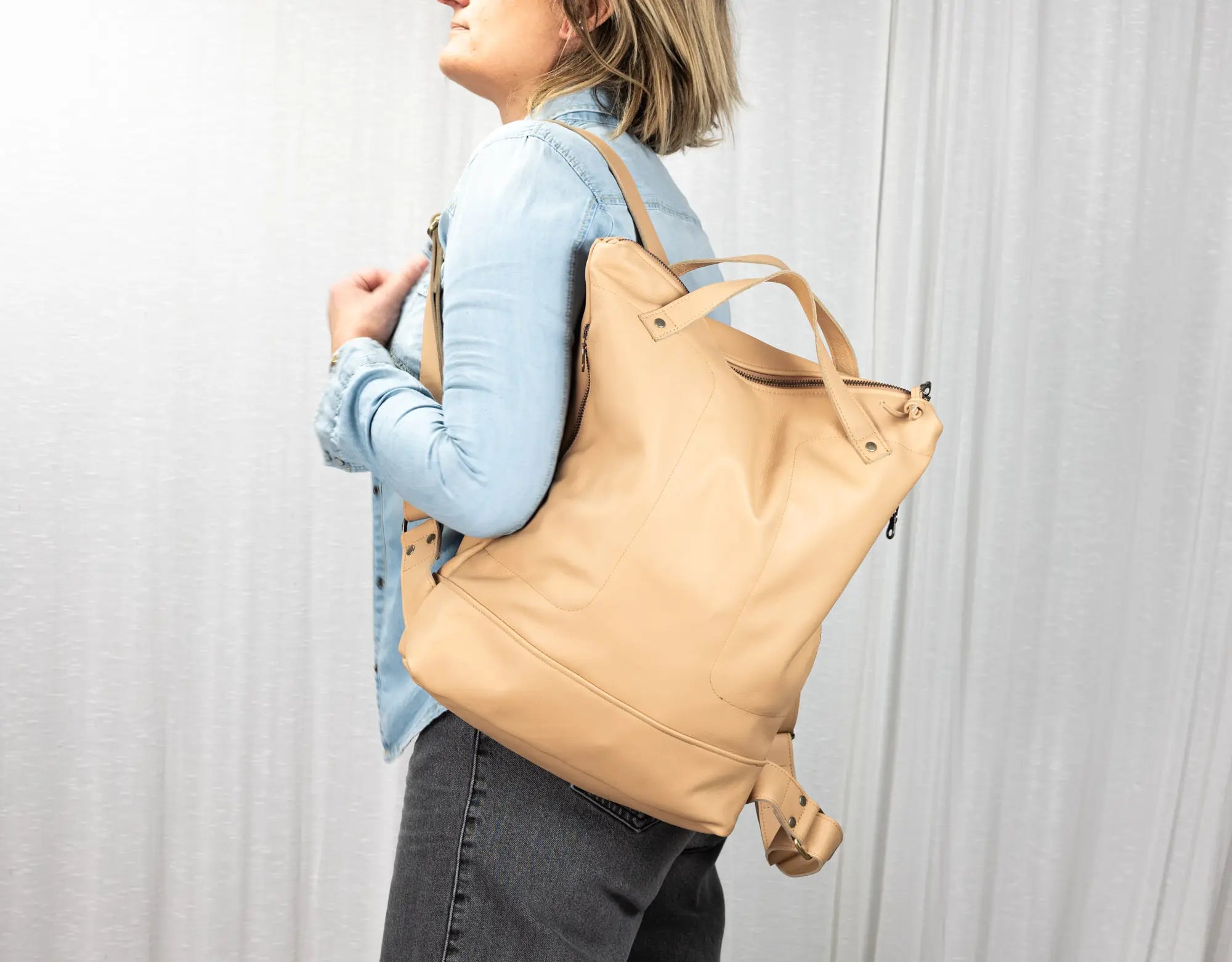 Person wearing a beige backpack against a plain background