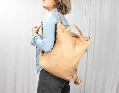 Person wearing a beige backpack against a plain background