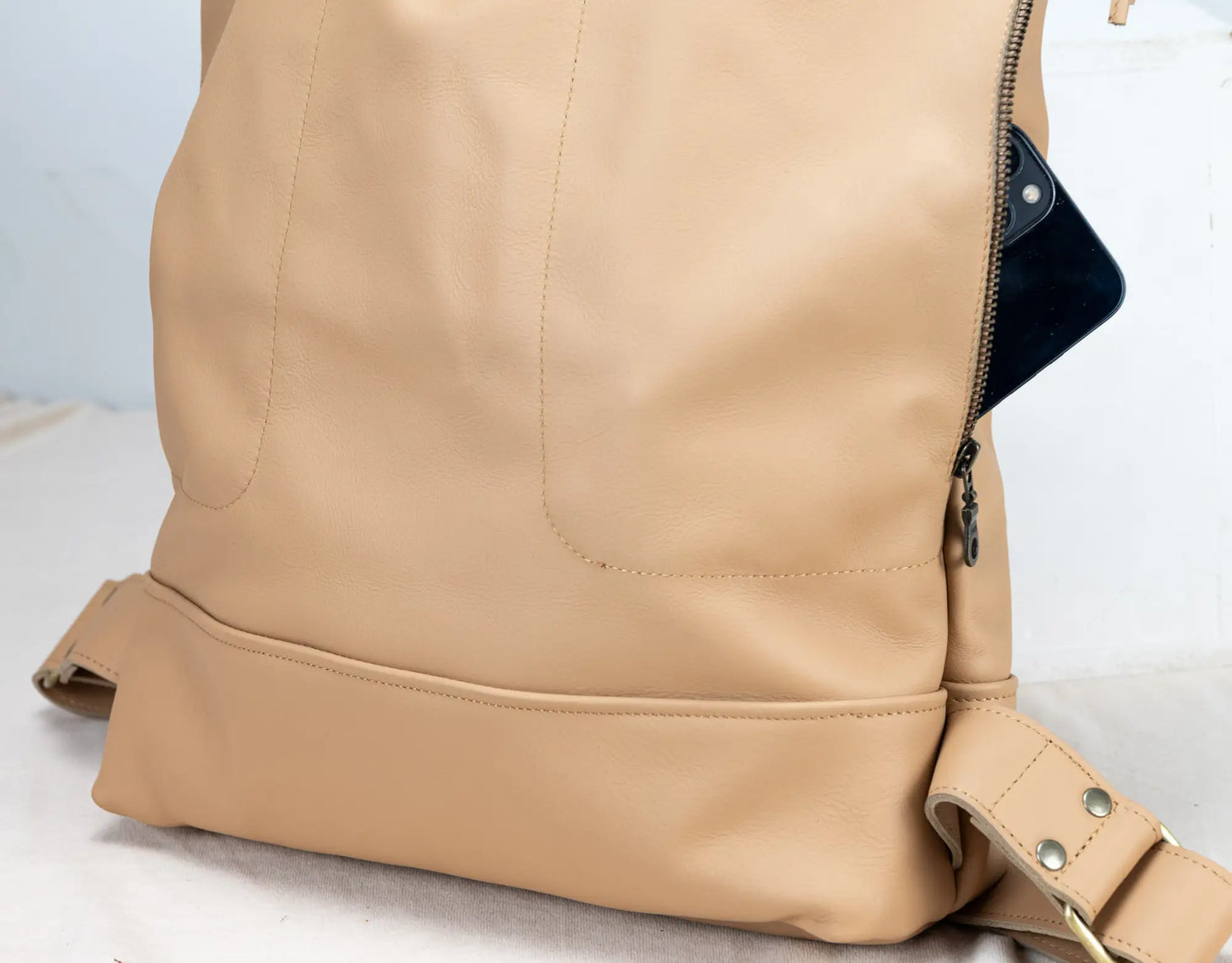 Close-up of a beige leather backpack on a light background