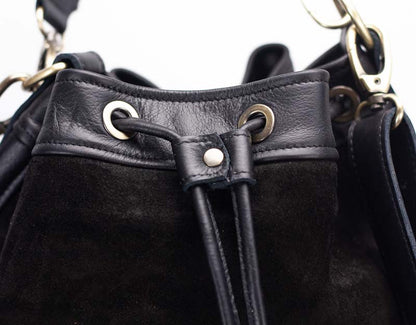 Close-up of a black leather drawstring bag with metal eyelets and a button.