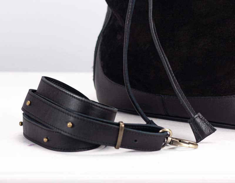 Black leather strap with gold hardware on a white background