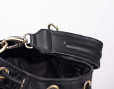 Close-up of a black leather bag with gold hardware on a white background