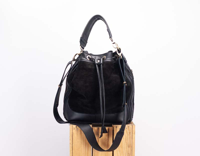 Black leather handbag on a wooden block with a white background