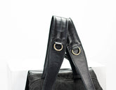 Black leather handbag with gold hardware on a white background