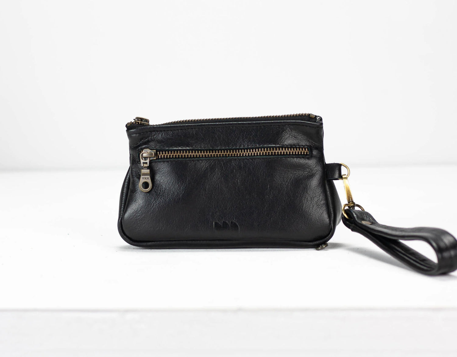 Black leather wristlet with a strap on a white background