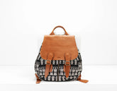 Backpack with black and white pattern and brown leather straps on a white background