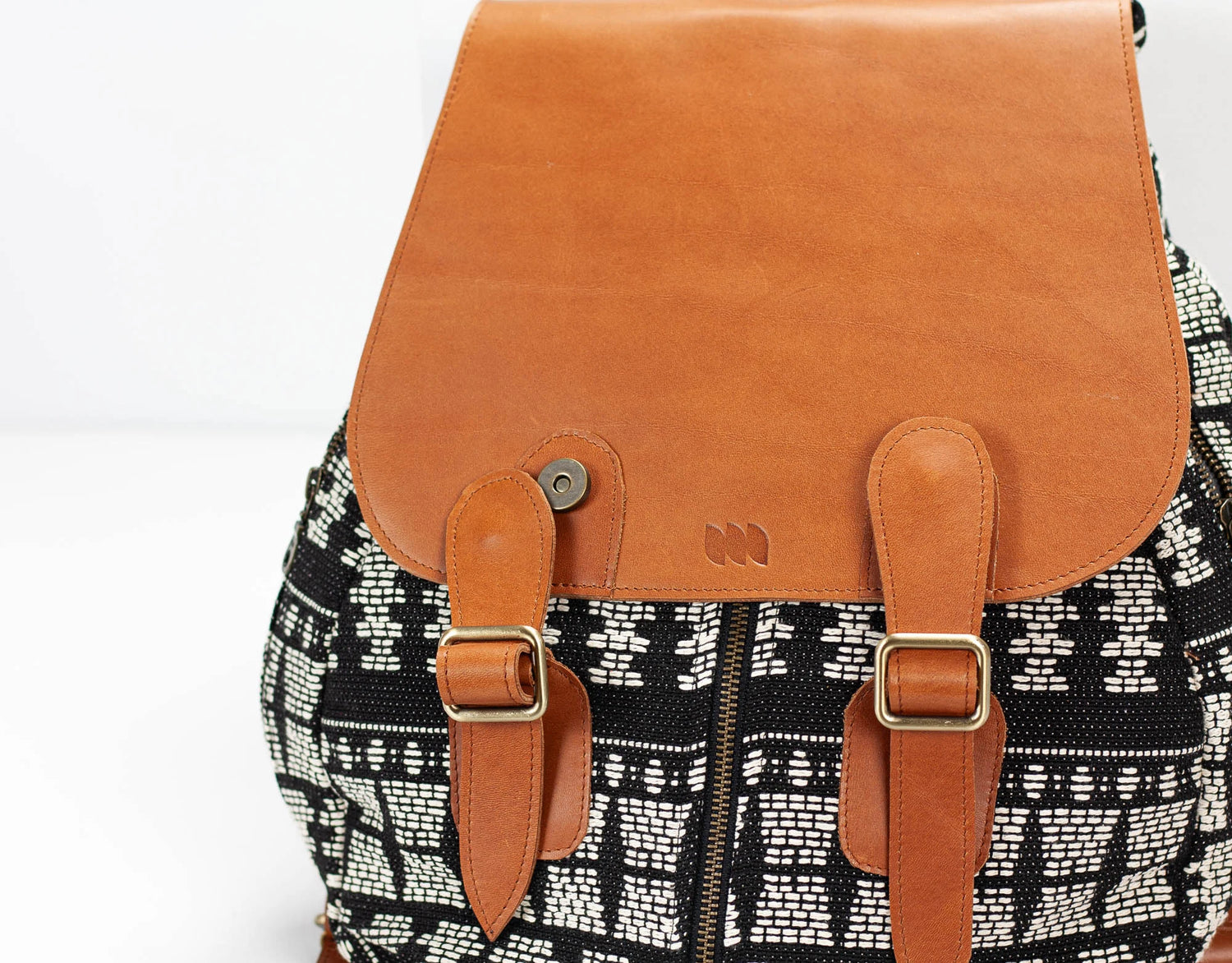 Backpack with brown leather straps and patterned fabric body on a white background