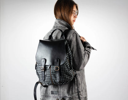 Person wearing a houndstooth pattern backpack with a plain background