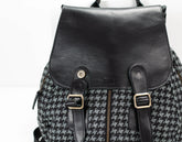 Black leather backpack with houndstooth pattern on a white background