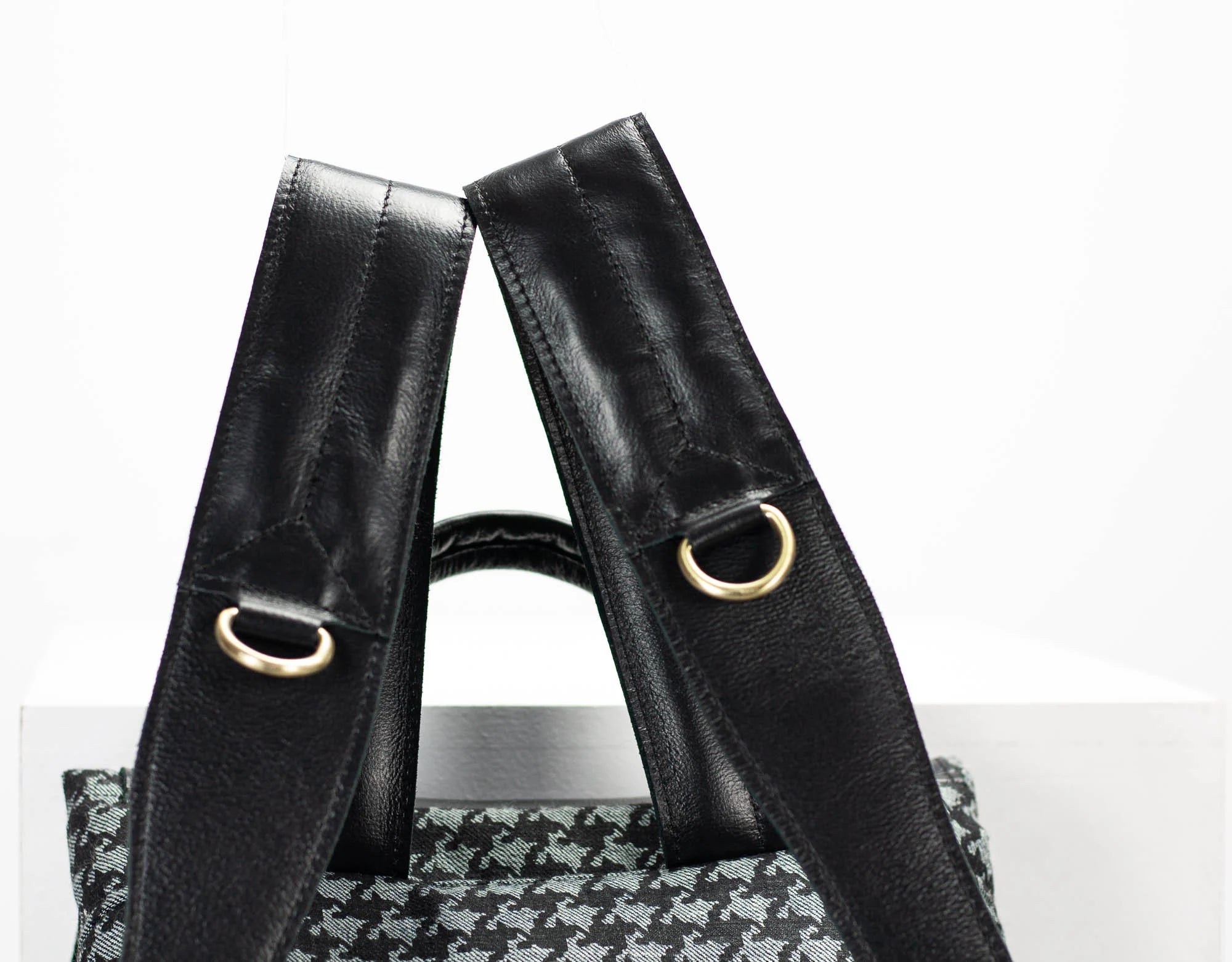 Black leather handbag with gold hardware on a white background