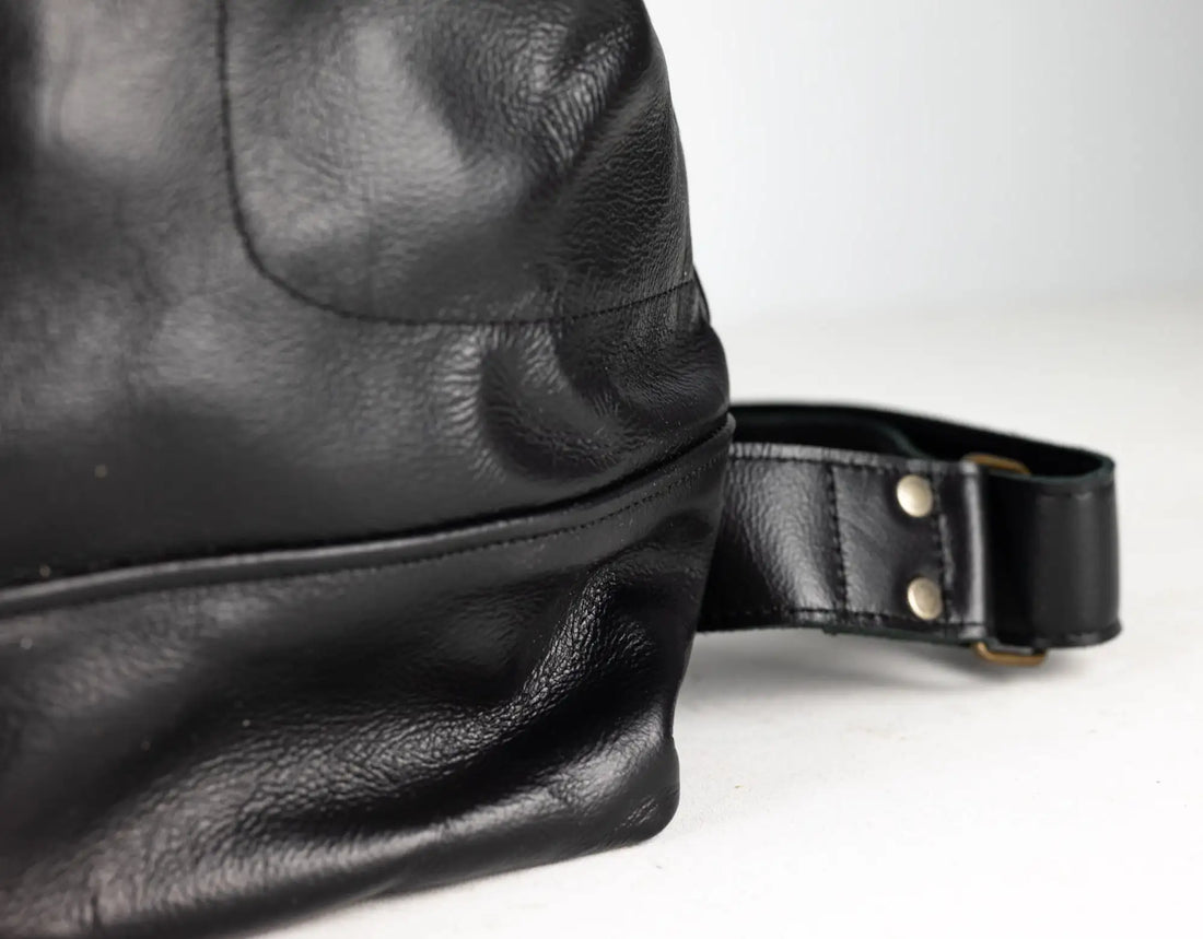 Close-up of a black leather bag with a strap on a white background
