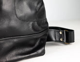 Close-up of a black leather bag with a strap on a white background