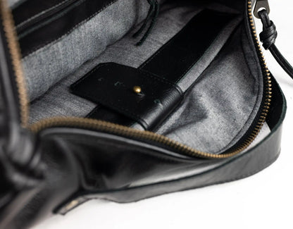 Black leather bag with a phone inside on a white background