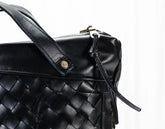 Black woven handbag with a strap on a white background
