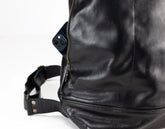 Close-up of a black leather bag with a strap on a white background