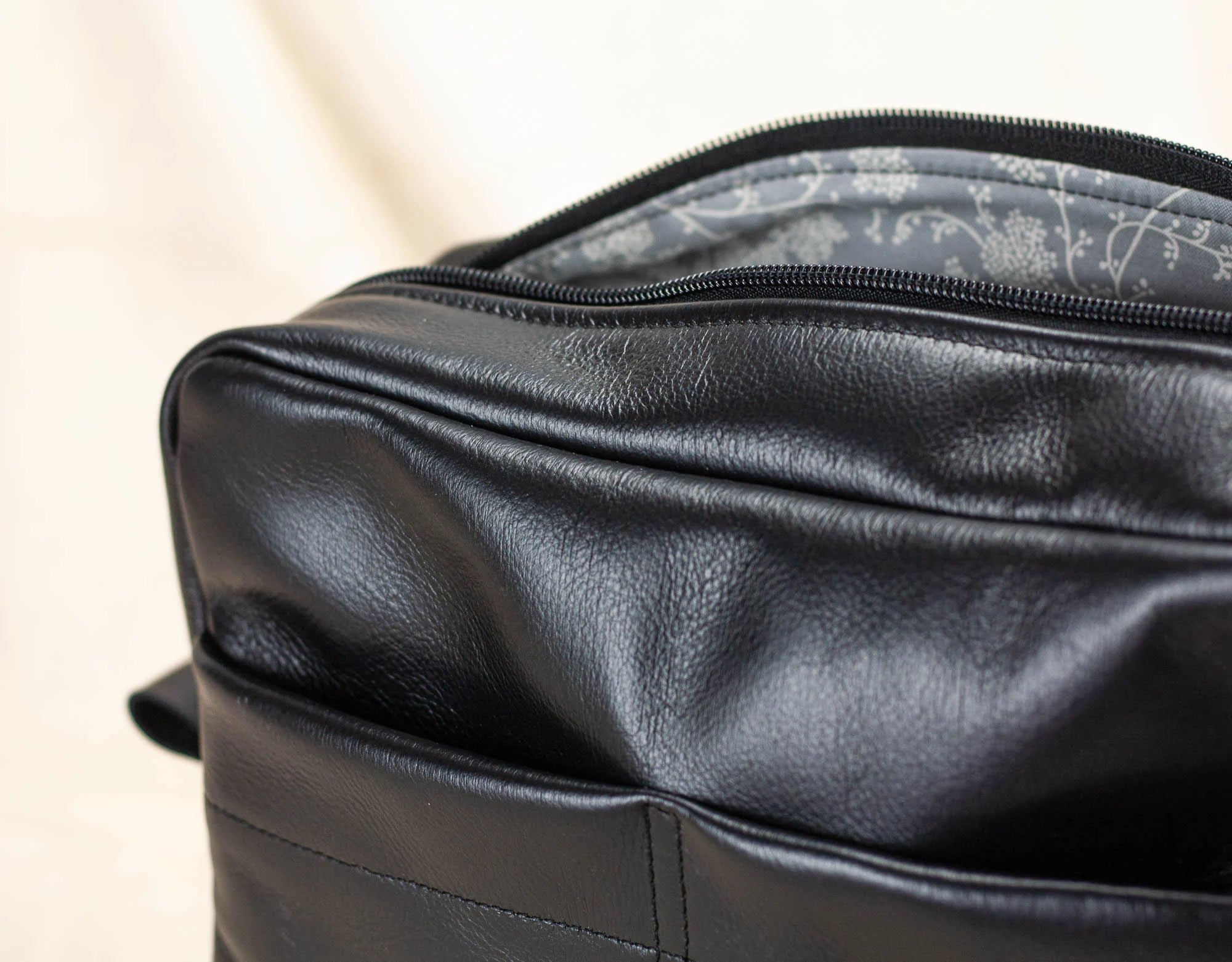 Black leather bag organizer with floral lining on a beige background