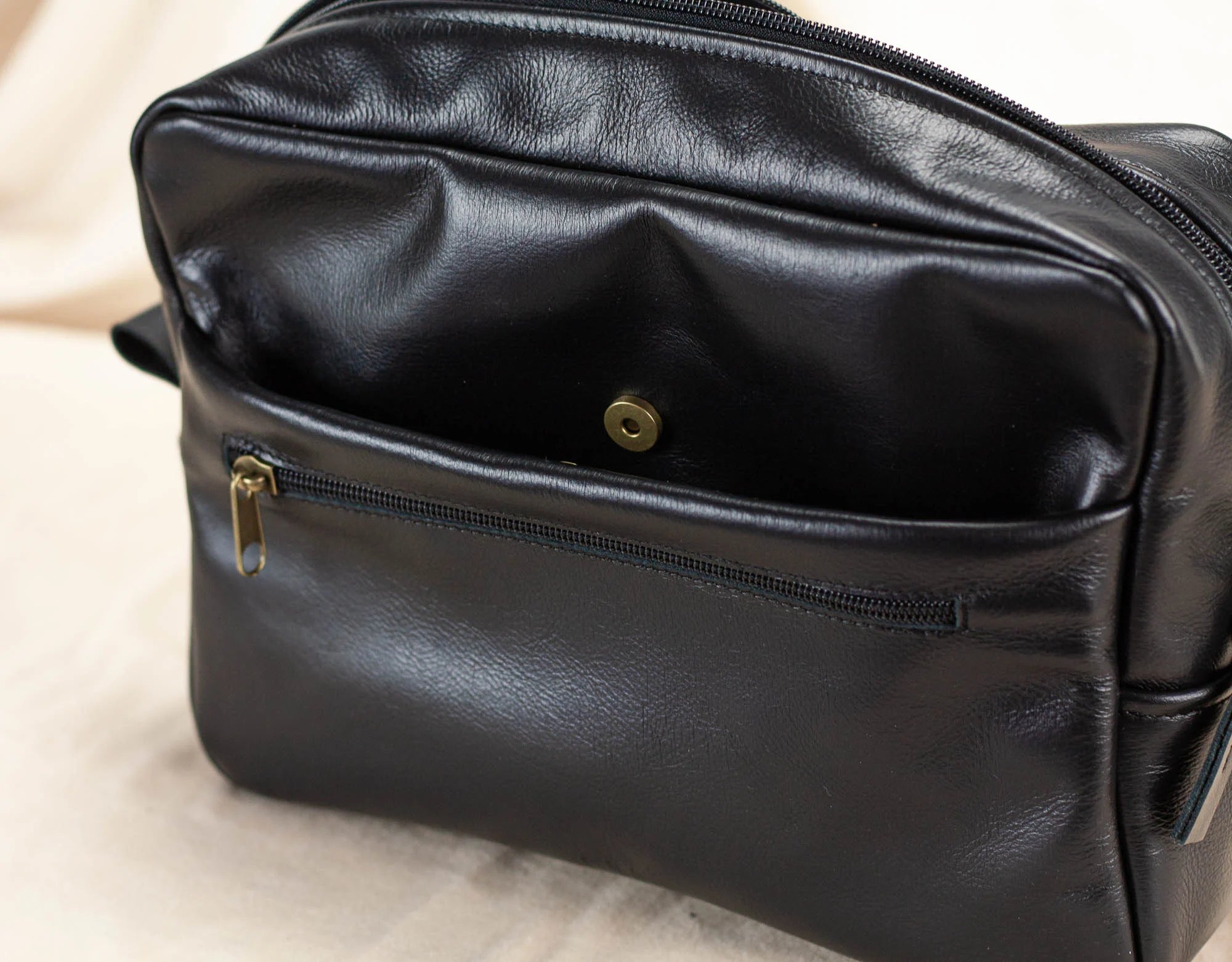Black leather bag insert with a gold zipper on a light background