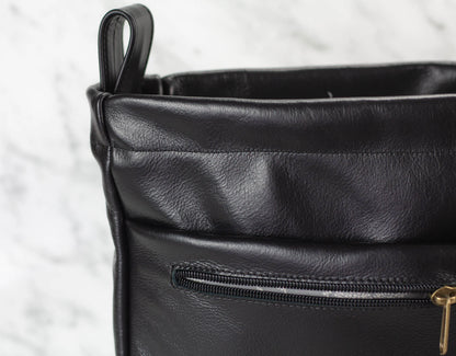 Close-up of a black leather bag organizer with a zipper on a light gray background