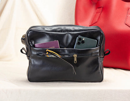 Black leather bag with a red bag in the background