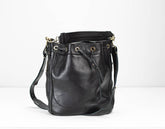 Black leather bucket bag with gold hardware on a white background