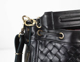 Black quilted leather handbag with gold hardware on a white background