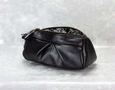 Black leather pouch with floral embroidery on a textured white background