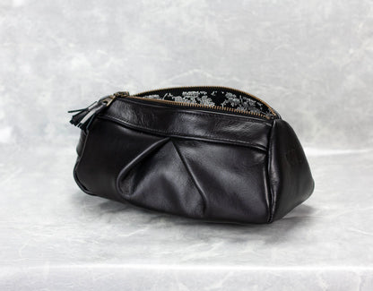 Black leather pouch with floral embroidery on a textured white background