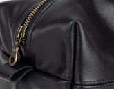 Close-up of a black leather bag with a gold zipper.