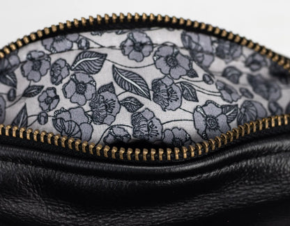 Close-up of a black leather pouch with a floral patterned interior.