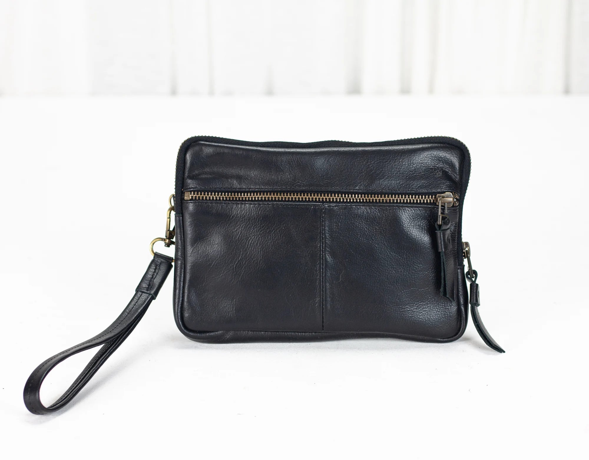 Black leather clutch bag with a strap on a white background
