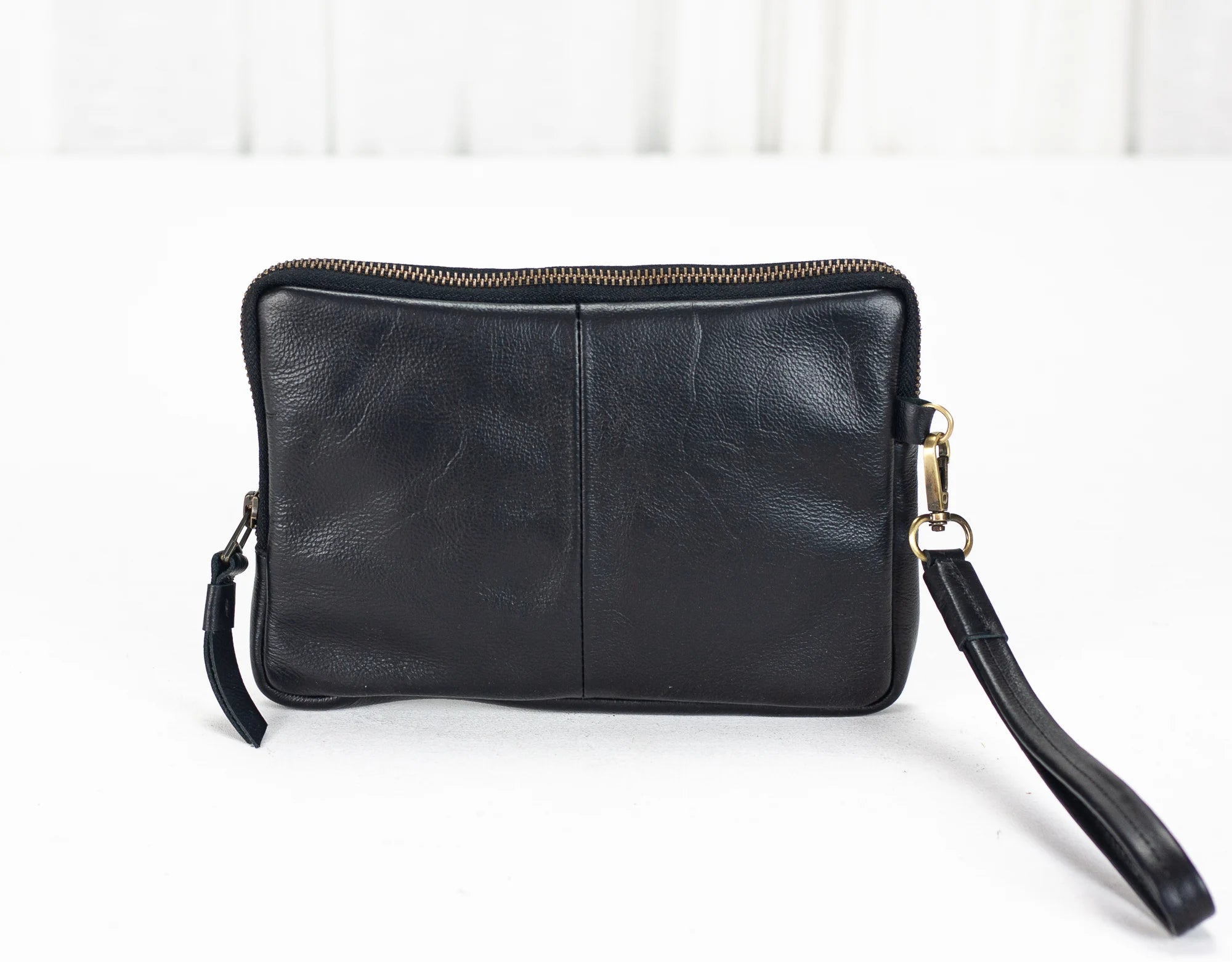 Black leather clutch bag with a strap on a white background