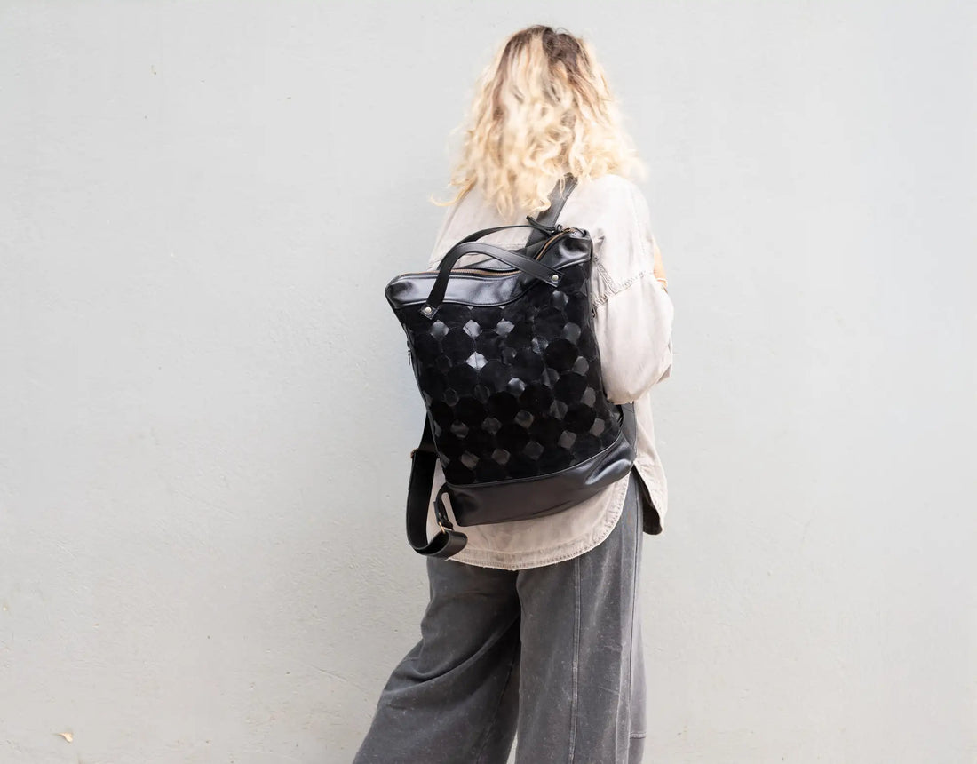Person wearing a black backpack with a pattern against a plain background