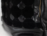 Close-up of a black leather handbag with geometric pattern