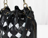 Black leather handbag with white geometric pattern on a light gray background