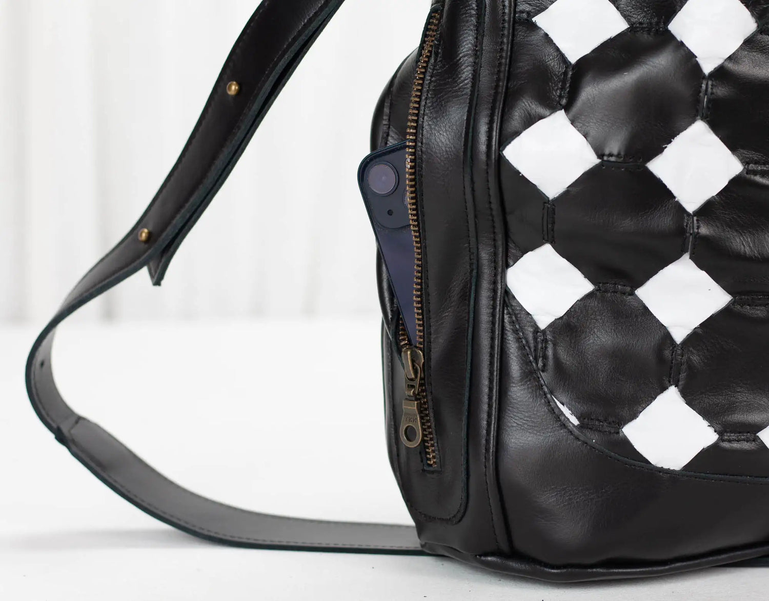 Black leather bag with checkered pattern on a white background