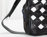 Black leather bag with checkered pattern on a white background