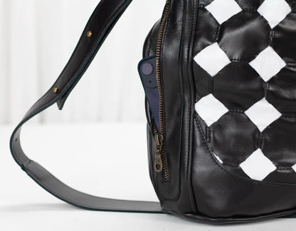 Black leather bag with checkered pattern on a white background