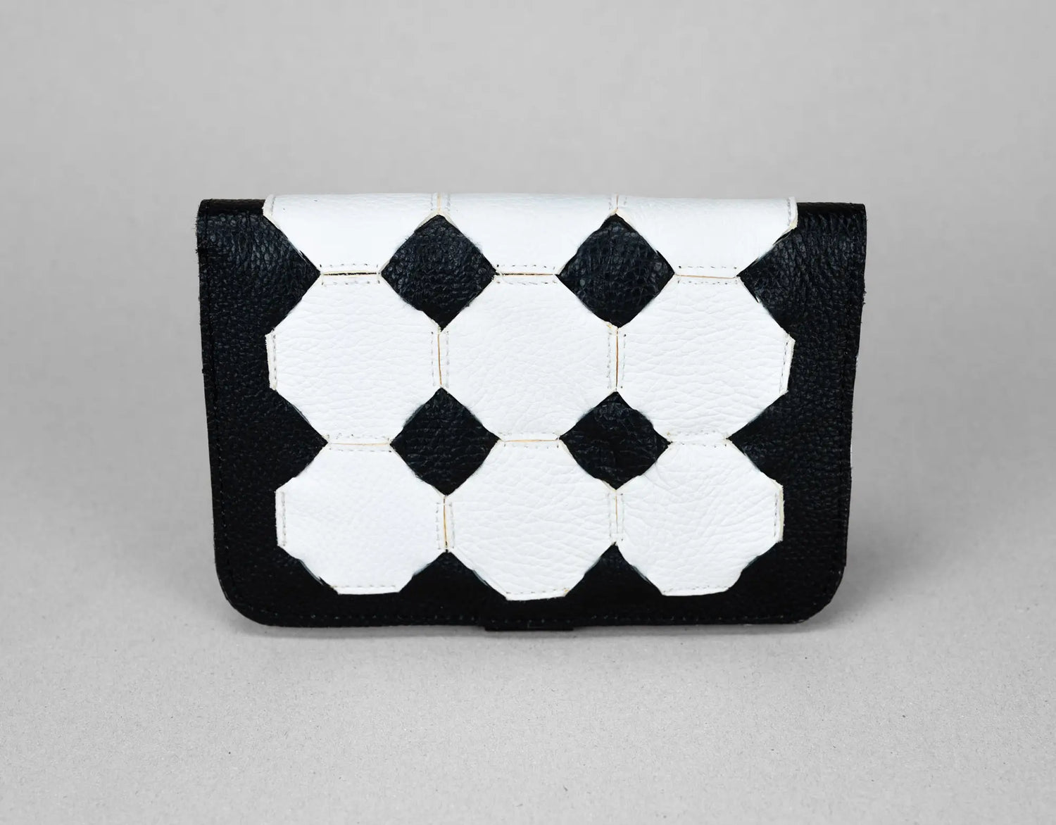 Black and white geometric patterned clutch bag on a gray background