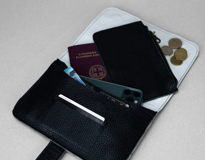 Black leather wallet with phone, cards, and coins on a light gray background