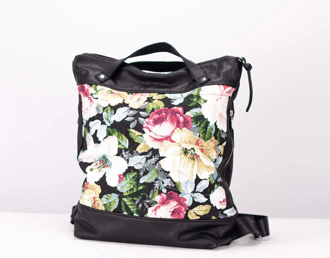 Floral-patterned tote bag with black leather accents on a white background