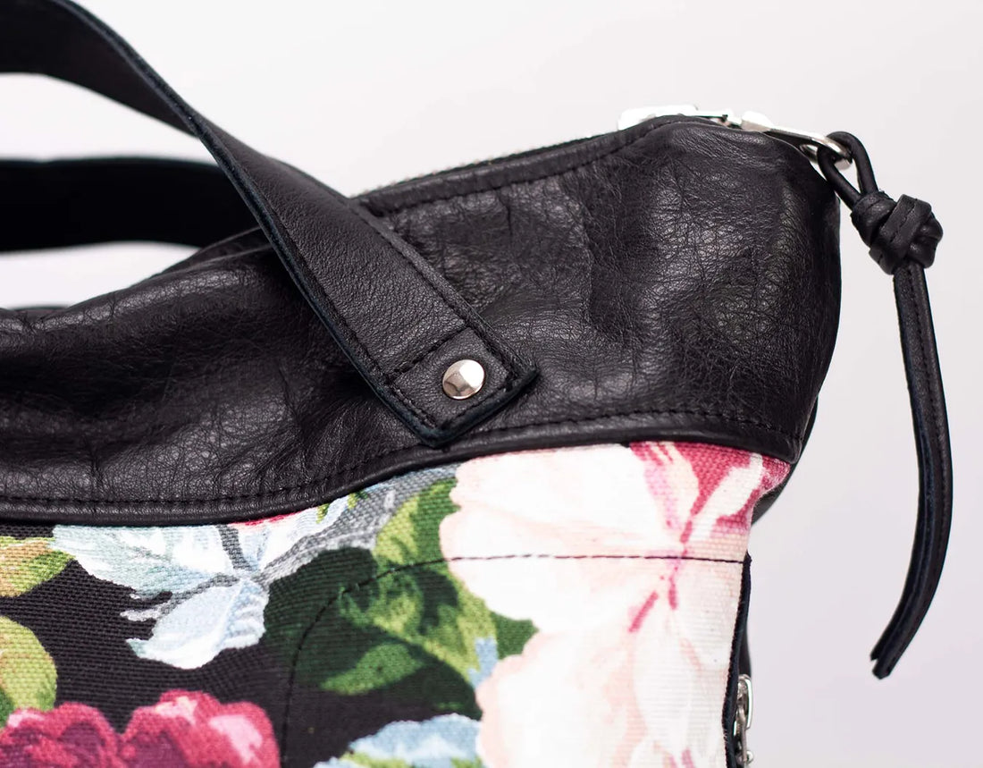 Black leather handbag with floral lining on a white background